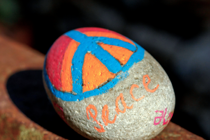 Bemalter Stein mit Peace-Zeichen und dem Wort „Peace“ als Symbol für Frieden.