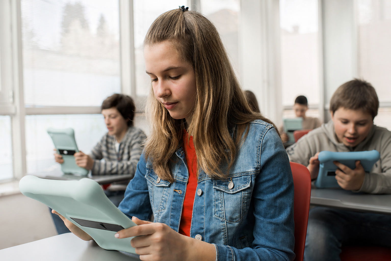 Schüler:innen sitzen in Klassenzimmer und arbeiten mit bunten Tablets